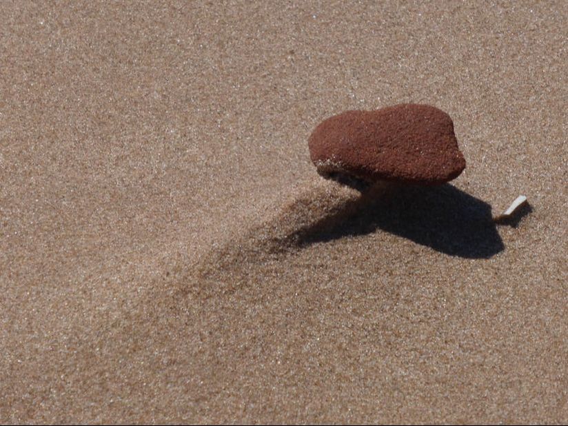 Red sandstone pebble on wind-scoured sand, PEI National Park, Canada.
